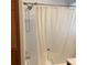 Tiled bathtub and shower combination with a white shower curtain and silver fixtures at 13111 Sunshine Cir, Clermont, FL 34711