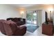 Comfortable living room featuring a brown sofa, recliner, and view of the backyard deck through sliding glass doors at 1389 Gainesville Ln, Deltona, FL 32725
