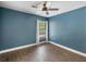 Bedroom with blue walls, white trim, wood tile floor, ceiling fan, and window with curtains at 1391 Terry Ln, Kissimmee, FL 34744