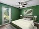 A serene green bedroom featuring a large window, comfortable bed, stylish decor, and ceiling fan at 1391 Terry Ln, Kissimmee, FL 34744
