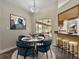 A bright dining area features a round table, stylish blue chairs, and a view to the outdoor living space at 1391 Terry Ln, Kissimmee, FL 34744