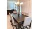 Dining area with a dark wood table, upholstered chairs, chandelier lighting, and sliding glass doors with decorative drapes at 16391 Admirals Cove Ln, Winter Garden, FL 34787