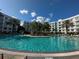 A large, inviting pool is surrounded by palm trees and lounge chairs for relaxation, within a multi-story building complex at 225 Celebration Pl # 527, Kissimmee, FL 34747