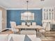 Dining area with modern chandelier, blue accent wall, light wood table, and bright natural light at 242 W Lyman Ave, Winter Park, FL 32789