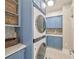 Laundry area with a modern stacked washer and dryer, blue cabinetry and countertops at 242 W Lyman Ave, Winter Park, FL 32789