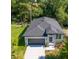 Aerial shot of a gray single-story house with a dark gray roof, lush trees, and a neatly landscaped front yard at 25 W 7Th St, Apopka, FL 32703