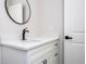 Bathroom vanity with black faucet, granite counters, and a round mirror at 25 W 7Th St, Apopka, FL 32703