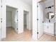 Hallway view with consistent flooring that leads to a nearby half-bath with a round, black framed mirror at 25 W 7Th St, Apopka, FL 32703