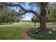 Beautiful backyard with manicured lawn, mature trees, and golf course views at 25859 Crossings Bluff Ln, Sorrento, FL 32776