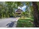 Community entrance with covered entryway, lush landscaping, and serene pond at 25859 Crossings Bluff Ln, Sorrento, FL 32776