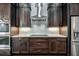 Close up of modern kitchen featuring a stainless steel vent hood and range with dark wood cabinets at 25859 Crossings Bluff Ln, Sorrento, FL 32776