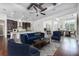 Open-concept living room featuring hardwood floors, modern furniture, a ceiling fan, and seamless flow to kitchen and dining areas at 25859 Crossings Bluff Ln, Sorrento, FL 32776