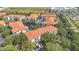 Aerial view of community featuring red-tiled roofs, a lake, mature trees, and a tennis court at 2627 Maitland Crossing Way # 101, Orlando, FL 32810
