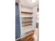 Open linen closet showing adjustable shelves in hallway with wood floor and bathroom in background at 2928 Ne 14Th Ave, Ocala, FL 34479