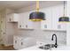 Bright kitchen featuring white cabinets, marble backsplash, stainless steel sink, and modern pendant lighting at 33 W 7Th St, Apopka, FL 32703
