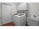 Laundry room with white appliances, cabinets, white door and terra cotta colored floors at 3518 Edlingham Ct, Belle Isle, FL 32812