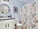 Bathroom with blue walls, modern vanity, round mirror, and white shower curtain with pink floral pattern at 455 Orange Ave, St Cloud, FL 34769