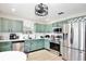 Stylish kitchen with stainless steel appliances, light green cabinetry and bright lighting at 455 Orange Ave, St Cloud, FL 34769