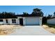 Charming single-story home with a white exterior, attached garage, and well-lit entryway at 506 St Johns Ct, Poinciana, FL 34759