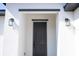 Close-up of the front door with modern light fixtures, contrasting trim, and white exterior at 506 St Johns Ct, Poinciana, FL 34759