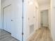 Hallway featuring multiple white doors, light gray wood-look floors and neutral paint throughout at 506 St Johns Ct, Poinciana, FL 34759