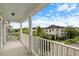 Covered balcony with white columns and railing, views of neighborhood homes, blue skies, and green landscaping at 5303 Brady Ln, Orlando, FL 32814