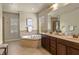 Bright bathroom featuring a soaking tub with tile surround and double vanity with dark cabinets and framed mirror at 5303 Brady Ln, Orlando, FL 32814