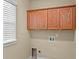 Bright laundry room features window with blinds and upper wood cabinets at 5303 Brady Ln, Orlando, FL 32814