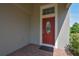 Close up of a red, oval-windowed front door with brick paver landing and grey exterior paint at 5908 Paxton Ct, Apopka, FL 32703