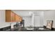 A galley style kitchen with granite countertops, wood cabinets and black appliances at 648 Kenwick Cir # 102, Casselberry, FL 32707