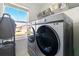 Modern laundry room features side-by-side washer and dryer units, with a view to the neighborhood at 700 Trotters Dr, Eagle Lake, FL 33839