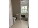 Cozy bathroom featuring a toilet and view of the bedroom with natural light, and white tile flooring at 707 Carpenters Way # 50, Lakeland, FL 33809