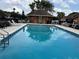 Community pool area with a pool house, palm trees, lounge chairs and clear blue water at 707 Carpenters Way # 50, Lakeland, FL 33809