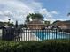 Community pool area with a pool house, palm trees, lounge chairs and black fencing at 707 Carpenters Way # 50, Lakeland, FL 33809