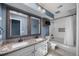 Well-lit bathroom with double sinks, granite counters, framed mirrors and a white tiled shower and bathtub at 8655 Shady Glen Dr, Orlando, FL 32819