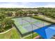 Overhead view of multiple tennis courts in a fenced-in area with lush trees and buildings in the background at 9644 Myrtle Creek Ln, Orlando, FL 32832
