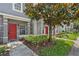 Charming townhome featuring a red front door, manicured landscaping, and a well-maintained walkway at 10914 Savannah Wood Dr # 139, Orlando, FL 32832