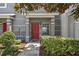 Charming townhome featuring a striking red front door, neutral gray siding, and well-maintained landscaping at 10914 Savannah Wood Dr # 139, Orlando, FL 32832