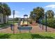 Community playground featuring slides, climbing structures, a bench, and monkey bars under a sunny sky at 10914 Savannah Wood Dr # 139, Orlando, FL 32832