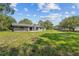 Expansive backyard featuring a gray home exterior, green grass and mature trees, perfect for outdoor activities at 1189 Rib Ave, St Cloud, FL 34771