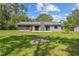 View of a gray home exterior, a well-maintained lawn, and surrounding greenery for a serene outdoor space at 1189 Rib Ave, St Cloud, FL 34771