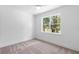 Bright bedroom featuring neutral carpet, white walls, and a window overlooking a green landscape at 1394 Kettledrum Trl, Deltona, FL 32725