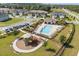 Aerial view of the community pool area with a playground, lounge chairs, and neighborhood streets at 1401 Mirabella Cir, Davenport, FL 33897