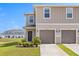 Charming two-story townhome featuring a two-car garage and well-manicured landscaping against a clear blue sky at 1401 Mirabella Cir, Davenport, FL 33897