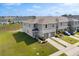 Exterior elevation of the townhome community, featuring lush green space and paved driveway at 1401 Mirabella Cir, Davenport, FL 33897
