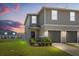 Charming two-story townhome featuring an attached garage, manicured lawn and inviting facade at sunset at 1401 Mirabella Cir, Davenport, FL 33897