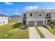 Well-maintained two-story townhome featuring an attached garage and manicured lawn on a sunny day at 1401 Mirabella Cir, Davenport, FL 33897