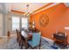 Stylish dining room featuring a large dining table with seating, modern chandelier, and decorative orange accent wall at 14830 Winkfield Ct, Winter Garden, FL 34787