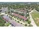 An aerial view showing a neighborhood of townhomes with tree-lined streets and green spaces at 152 Riggings Way, Clermont, FL 34711
