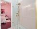 Bathroom showing a shower with gold trim and a view to the bedroom with pink walls at 152 Riggings Way, Clermont, FL 34711